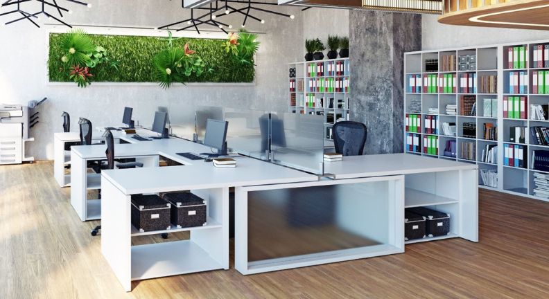 Ein modernes, helles Großraumbüro mit weißen Schreibtischen, ergonomischen Stühlen und grünen Pflanzen an den Wänden.